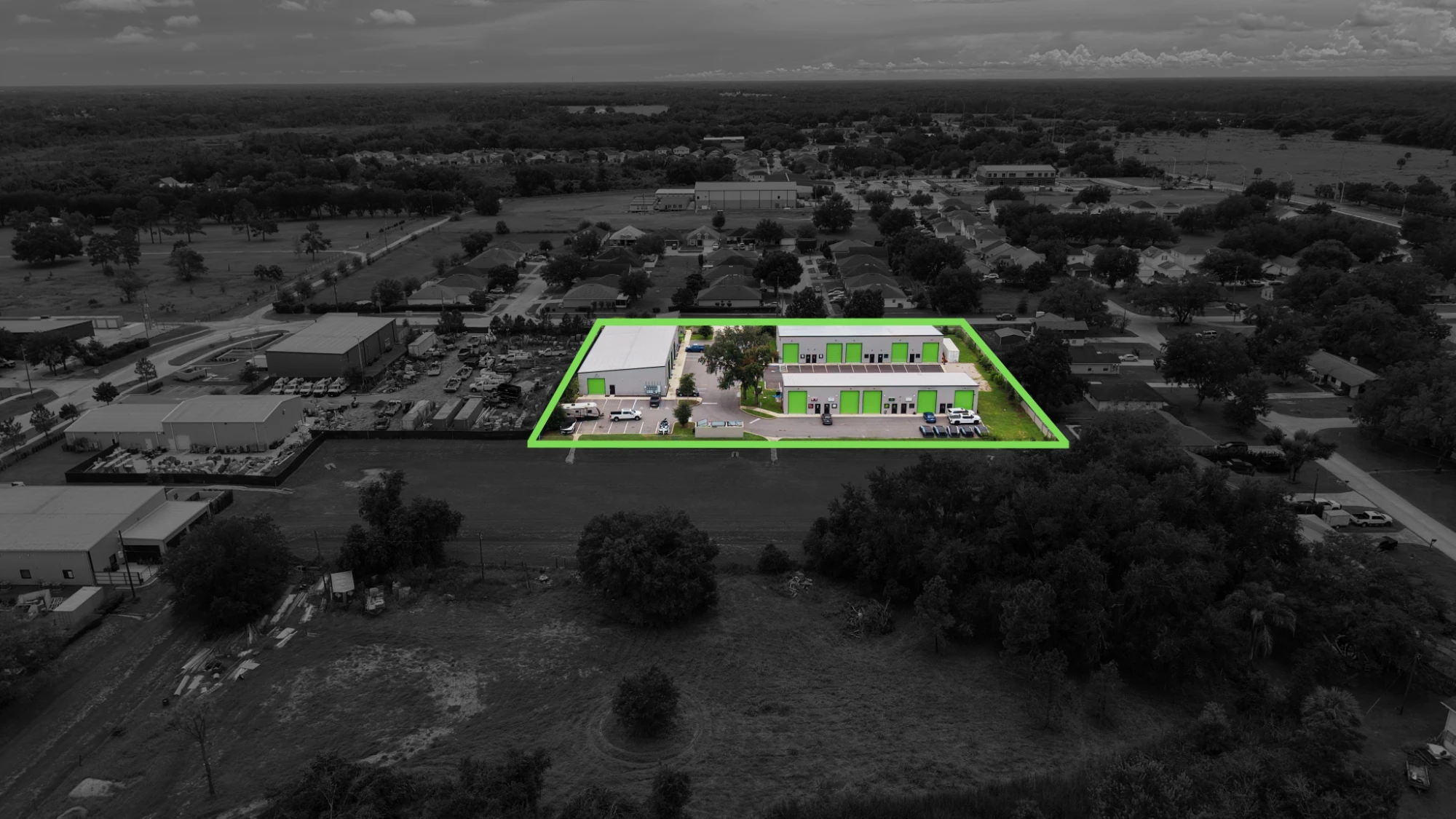 Aerial of a Central Florida flex warehouse property with the parcel boundary highlighted in green against a desaturated background